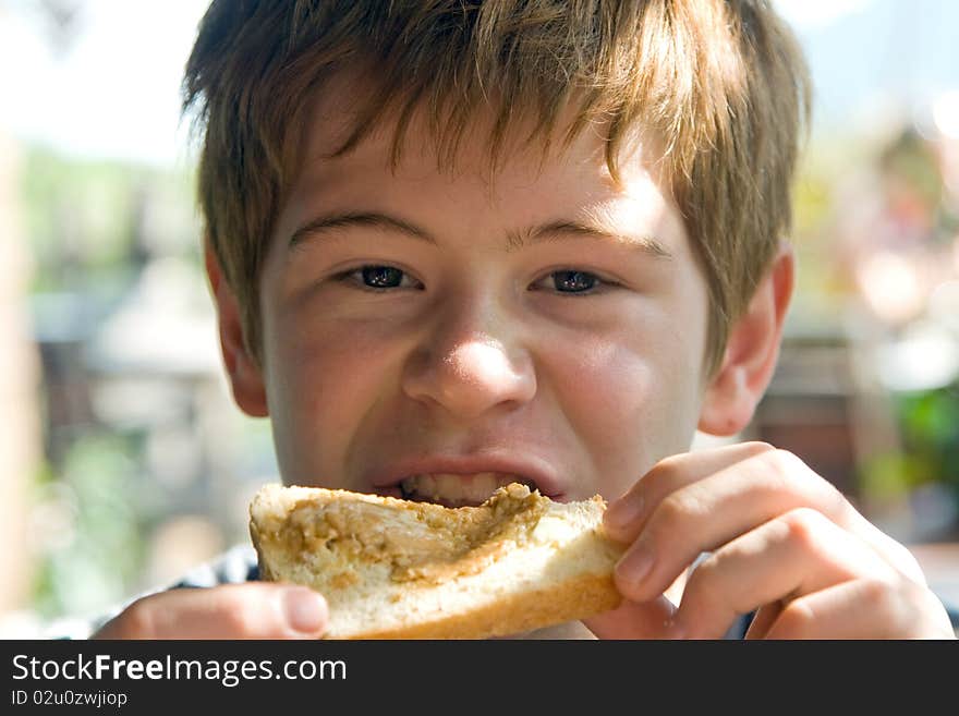 Joung boy is eating toast with cream on top, enjoing meal