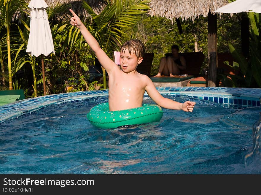 Young boy in a floting tyre enjoys the pool