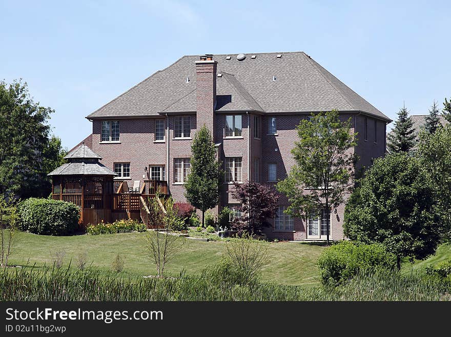 Rear view of large brick home with circular porch