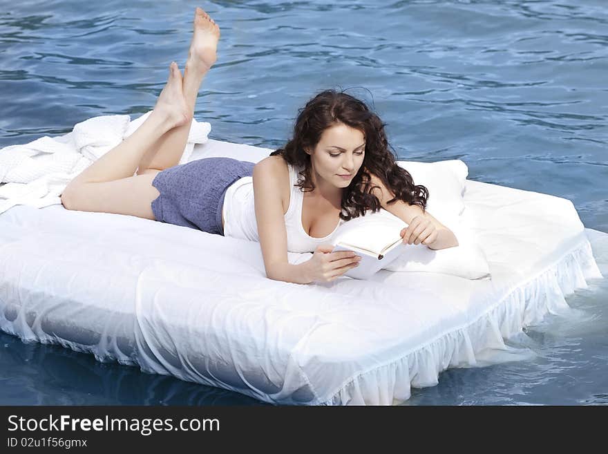 Beautiful young woman lying on the white bed in the sea. Beautiful young woman lying on the white bed in the sea