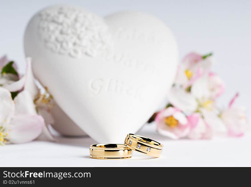 Two wedding rings with a heart and flowers in the background