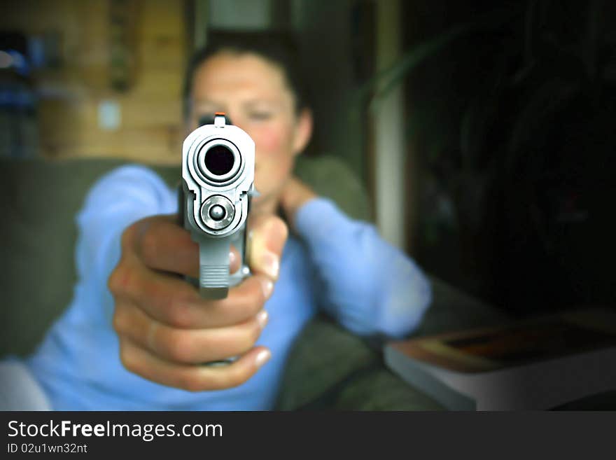 A young woman aims a nine millimeter pistol at the camera. A young woman aims a nine millimeter pistol at the camera