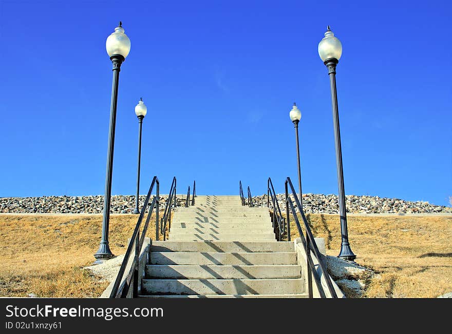 A stairway leading up to an unknown location with light poles on both sides. A stairway leading up to an unknown location with light poles on both sides.