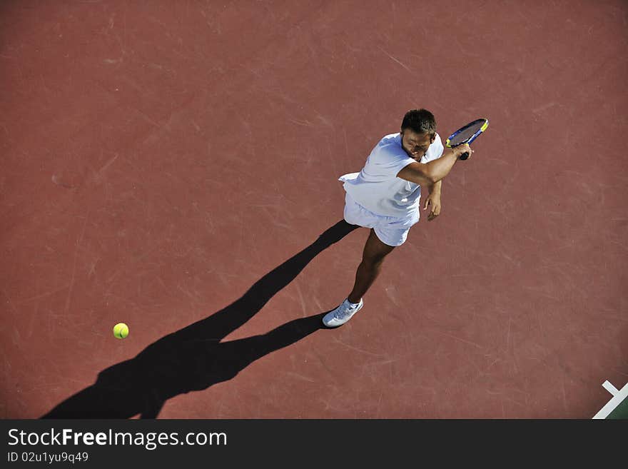 Young man play tennis outdoor on orange tennis field at early morning