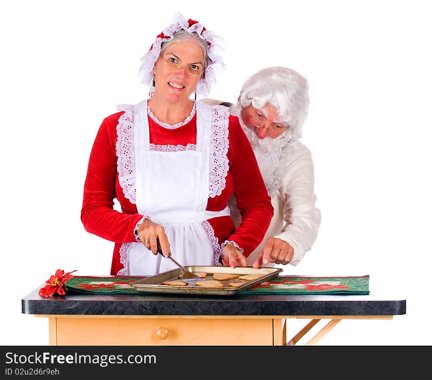 Santa attempting to snitch one of Mrs. Santa's cookies as she stakes them up from a cookie tin.  Isolated on white. Santa attempting to snitch one of Mrs. Santa's cookies as she stakes them up from a cookie tin.  Isolated on white.