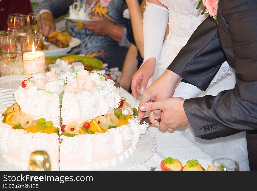 Just married are cuting the wedding cake on the table