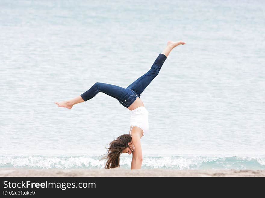 Young girl doing gymnastics on sea background