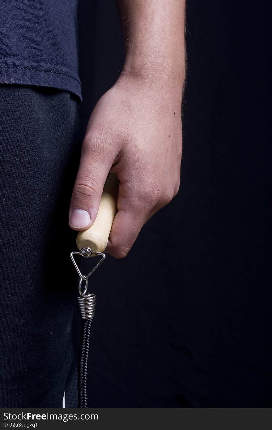 Human hand holding a jump rope on a black background.