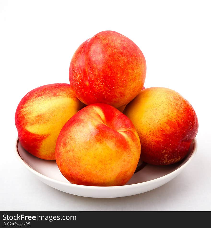 Four  juicy peaches with  smooth, thin, brightly colored skin  on the dish on white background. Four  juicy peaches with  smooth, thin, brightly colored skin  on the dish on white background