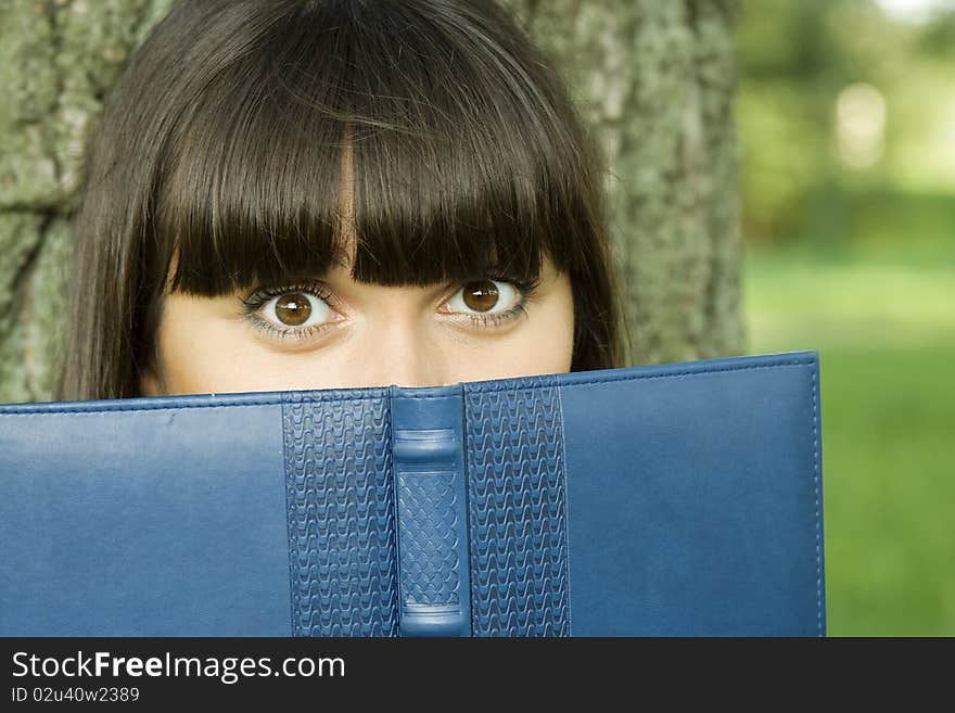 Young beautiful woman in a park with a notebook. Young beautiful woman in a park with a notebook.