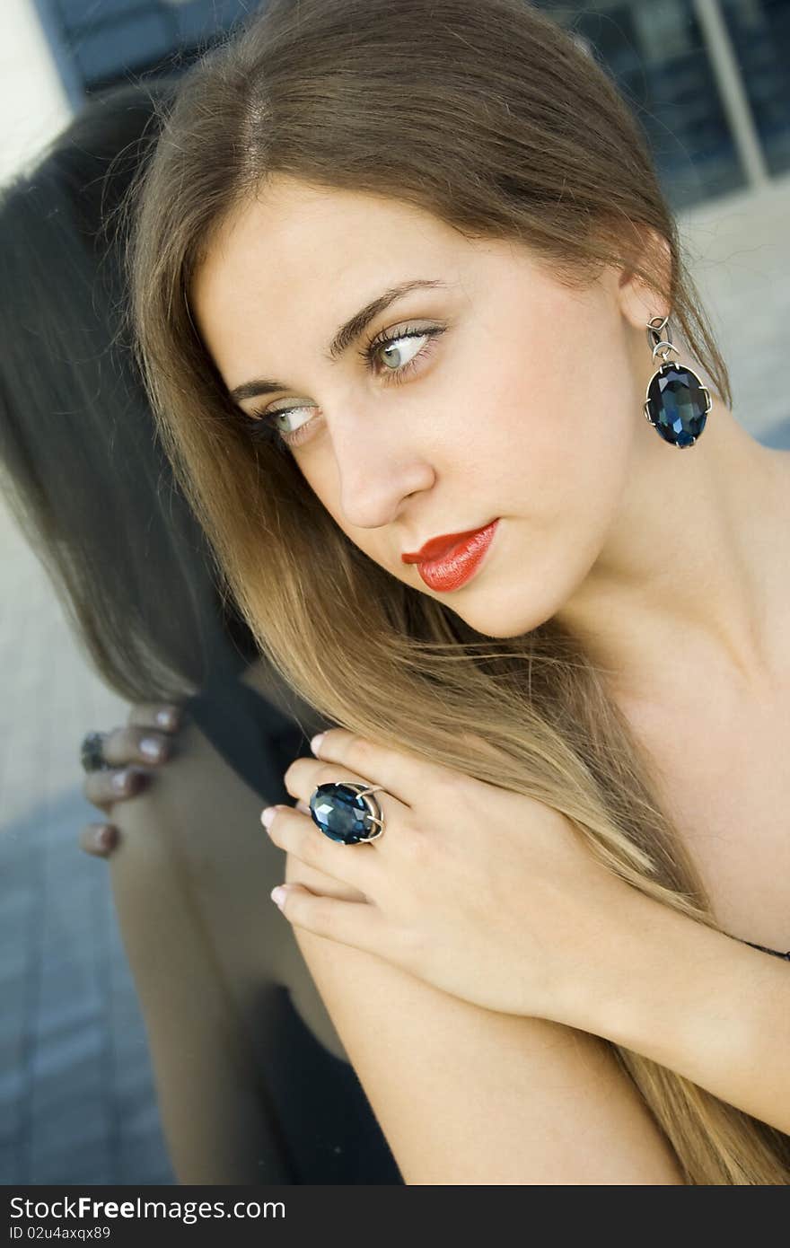 Portrait of elegantly beautiful young woman. The girl beautiful jewelry, ring and earrings with large blue stones. Portrait of elegantly beautiful young woman. The girl beautiful jewelry, ring and earrings with large blue stones