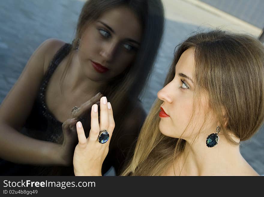 Portrait of elegantly beautiful young woman. The girl beautiful jewelry, ring and earrings with large blue stones. Portrait of elegantly beautiful young woman. The girl beautiful jewelry, ring and earrings with large blue stones