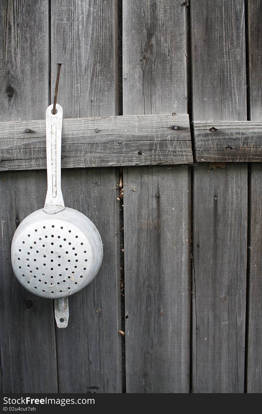 Sieve hanging on weathered wood panels, vertical image. Sieve hanging on weathered wood panels, vertical image