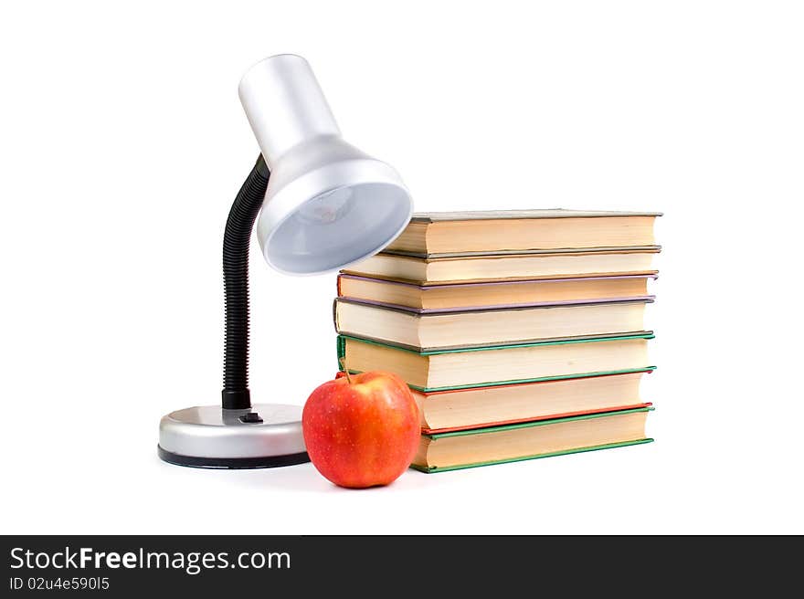 Table lamp, apple and books on white background