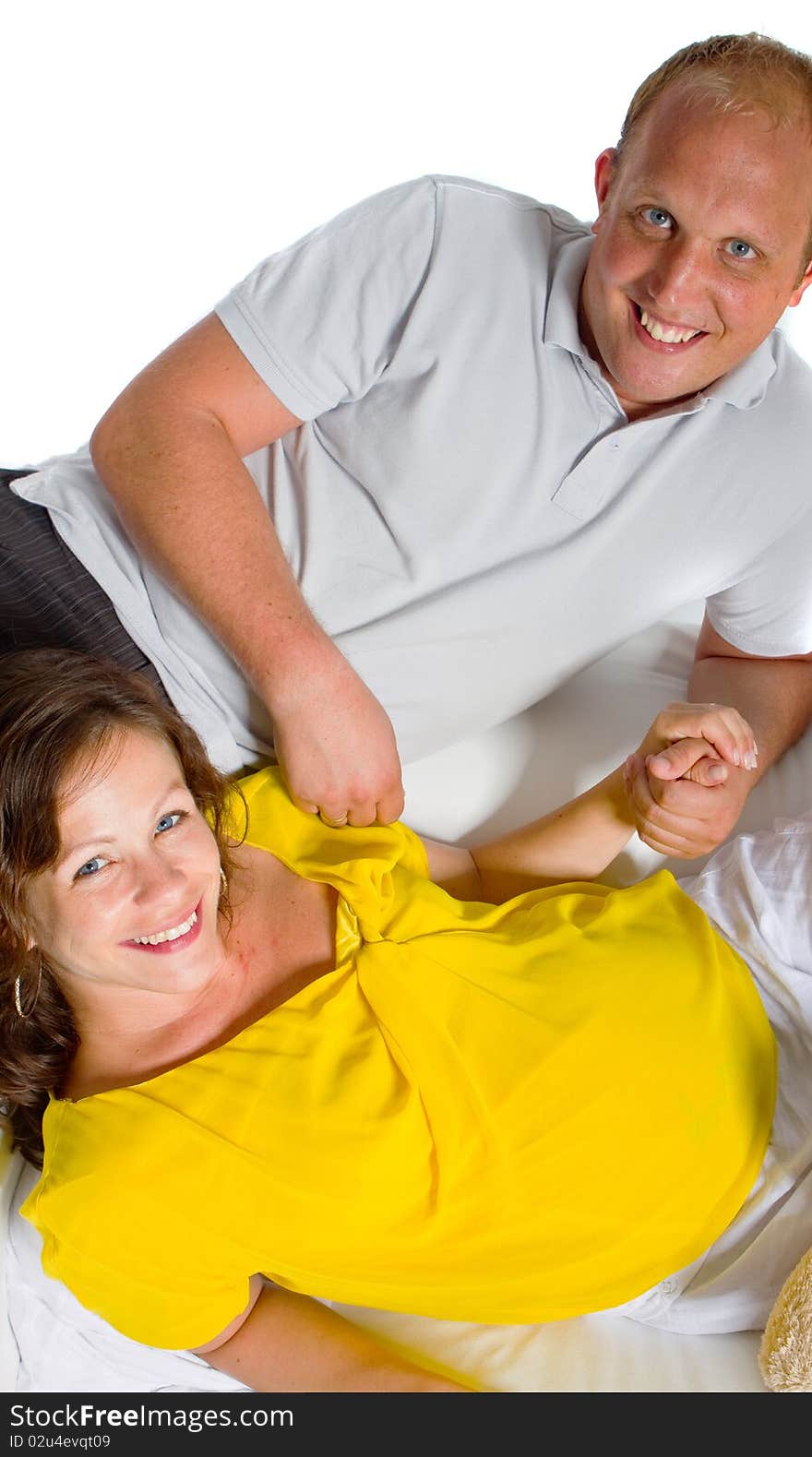 Young couple on a couch. The woman is pregnant and they seem to be in love. Young couple on a couch. The woman is pregnant and they seem to be in love.