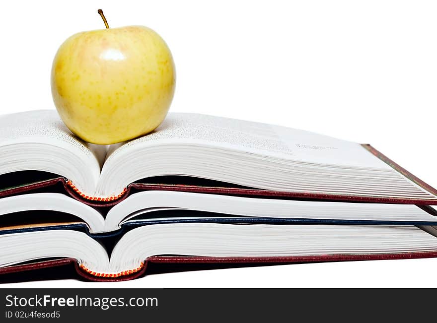 Stack of books and green apple on a white background