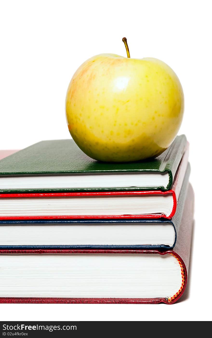 Stack of books and green apple on a white background