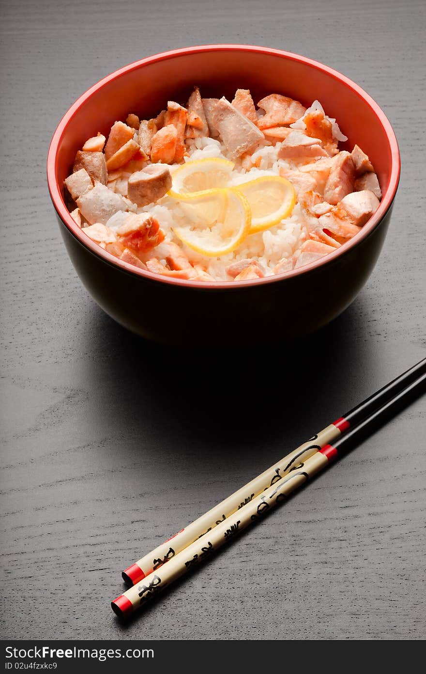 A close-up of chopsticks and a soup plate with delicious mixture of rice and fried fishes. A close-up of chopsticks and a soup plate with delicious mixture of rice and fried fishes.