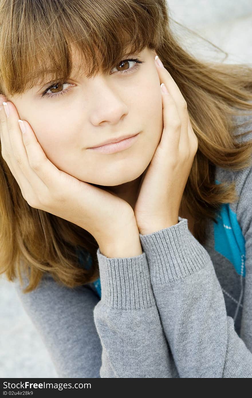 Portrait of a beautiful girl. A girl in a sweater with his hands propping up her head. Portrait of a beautiful girl. A girl in a sweater with his hands propping up her head