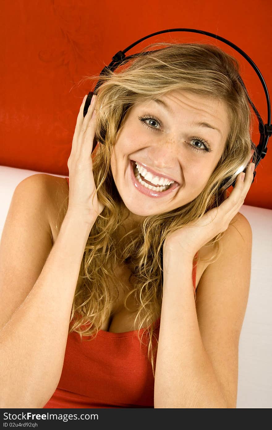 Young Girl loves listening to music with headphones sitting on the sofa. Young Girl loves listening to music with headphones sitting on the sofa