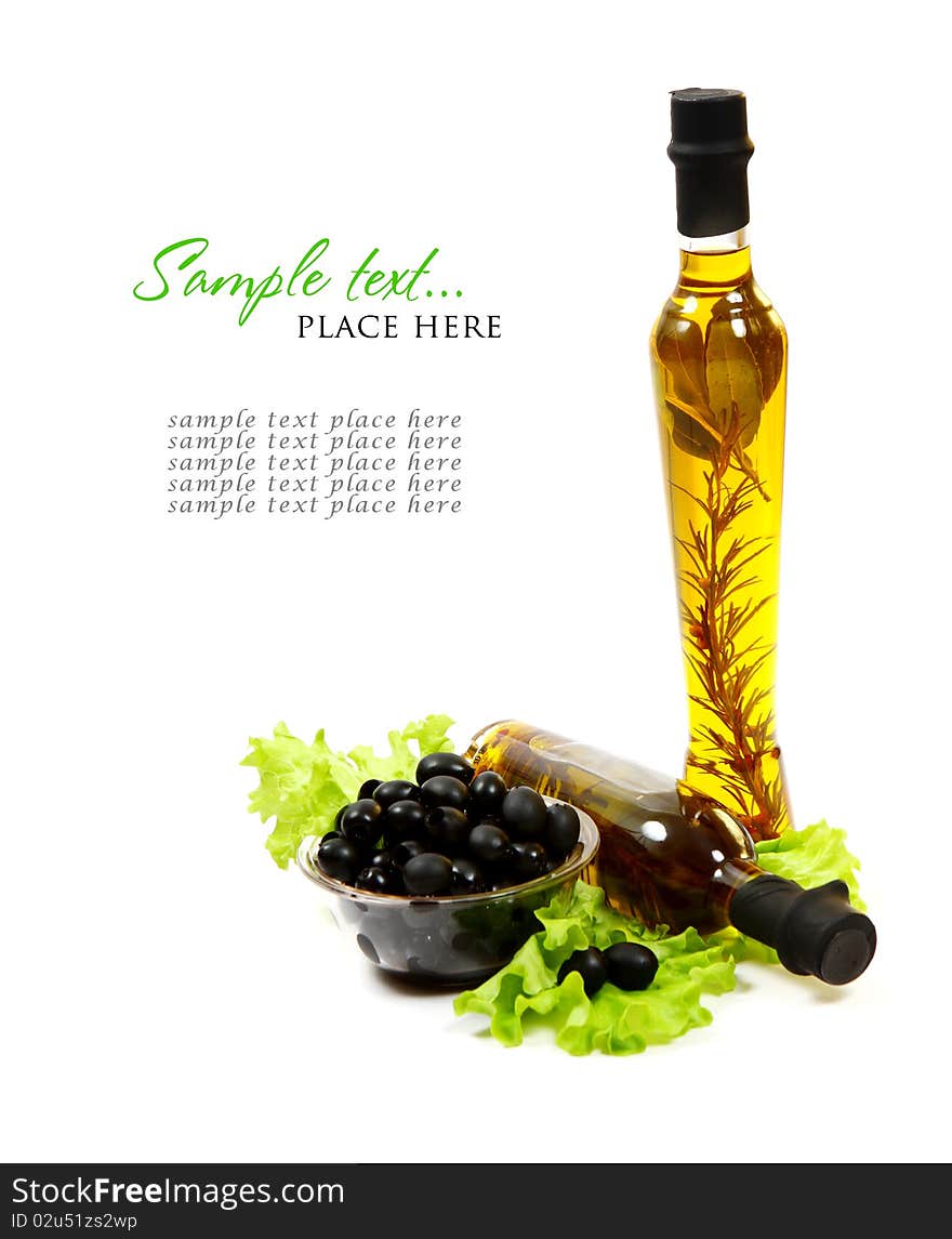 A bottle of olive oil with herbs and black olives isolated on a white background.