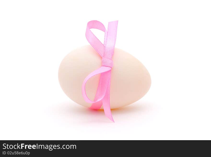 White egg wrapped around with pink ribbon over white background. White egg wrapped around with pink ribbon over white background