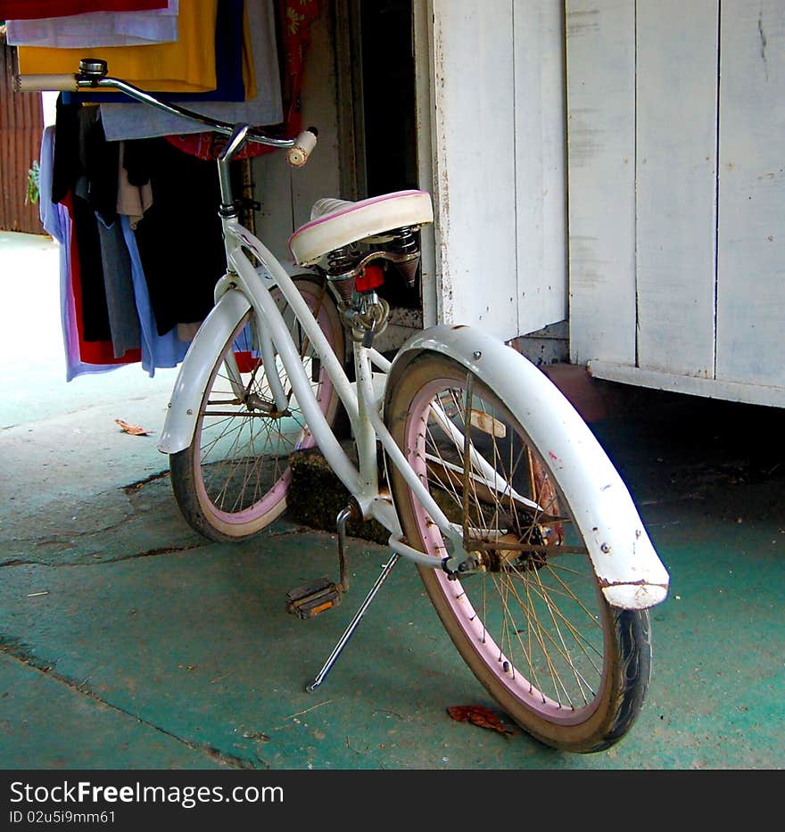 An old distressed girly bicycle in white and pink waiting to be used. An old distressed girly bicycle in white and pink waiting to be used