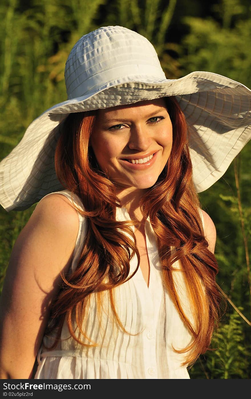 Portrait of a beautiful redhead with a white wide brim sun hat. Portrait of a beautiful redhead with a white wide brim sun hat