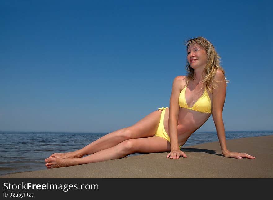 The beautiful woman sits on the beach. The beautiful woman sits on the beach