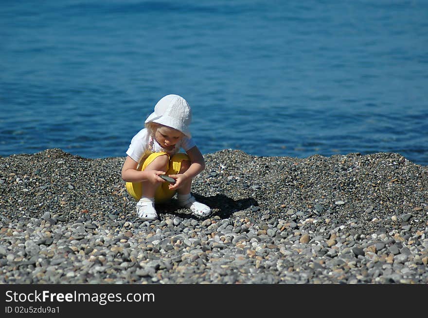 Small child sits on seaside