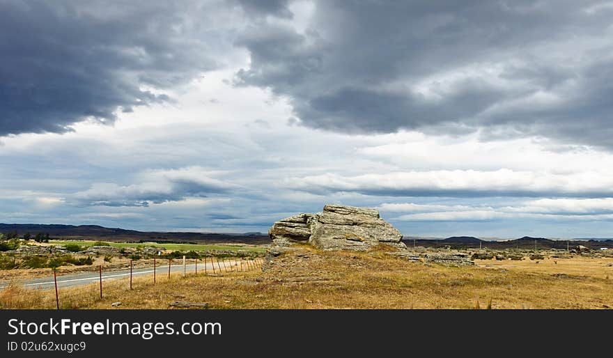 A rocky outcrop juts out of the Strath Taeri plains in the Maniototo, South Island, New Zealand