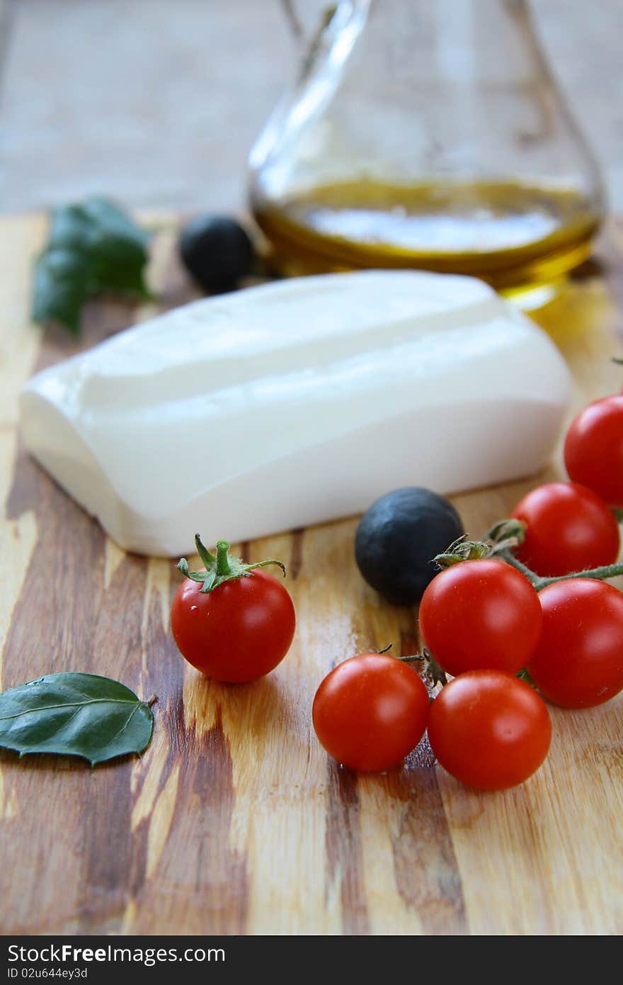 Cheese, tomatoes and olive oil on a wooden board