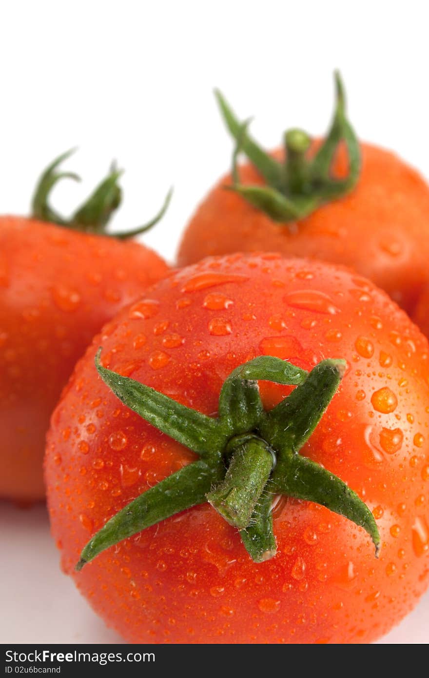 Three tomatoes with water drops.