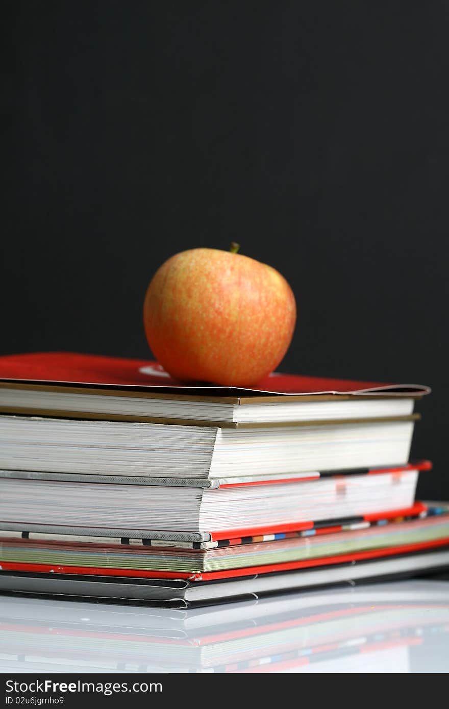 Red apple resting on the book with chalk board as background. Red apple resting on the book with chalk board as background