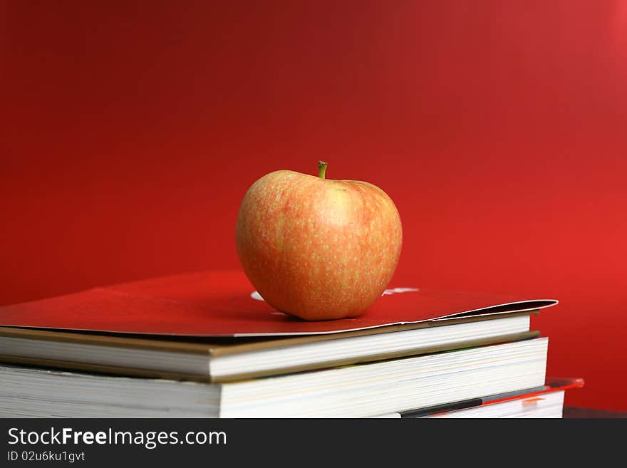 Red apple resting on the book with chalk board as background. Red apple resting on the book with chalk board as background