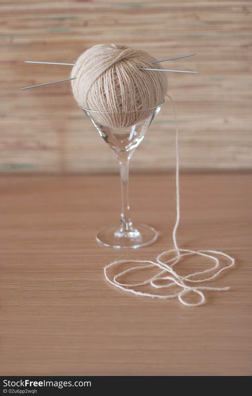 Ball of wool with needles in an elegant glass. Ball of wool with needles in an elegant glass