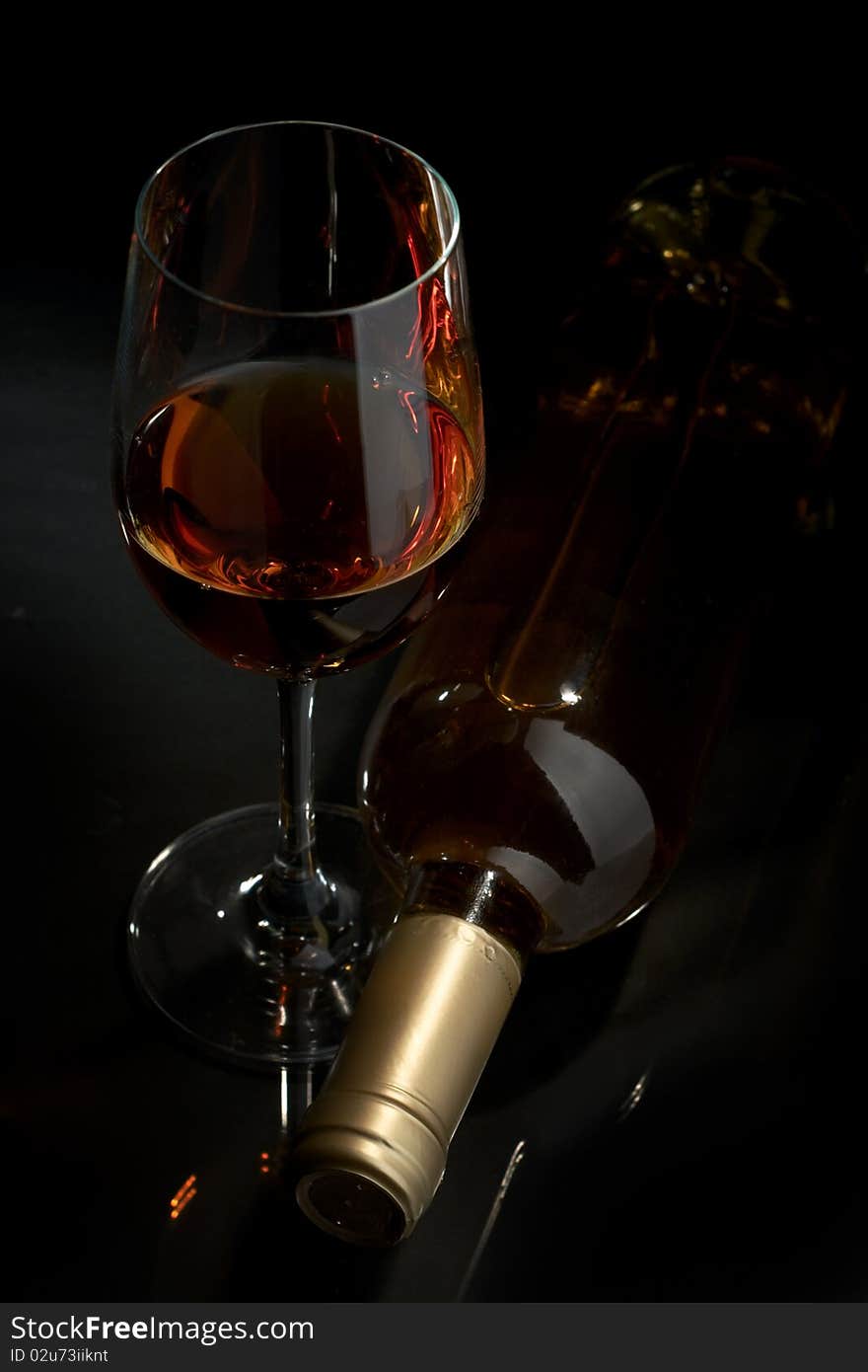 Bottle and glass of white wine on a dark background