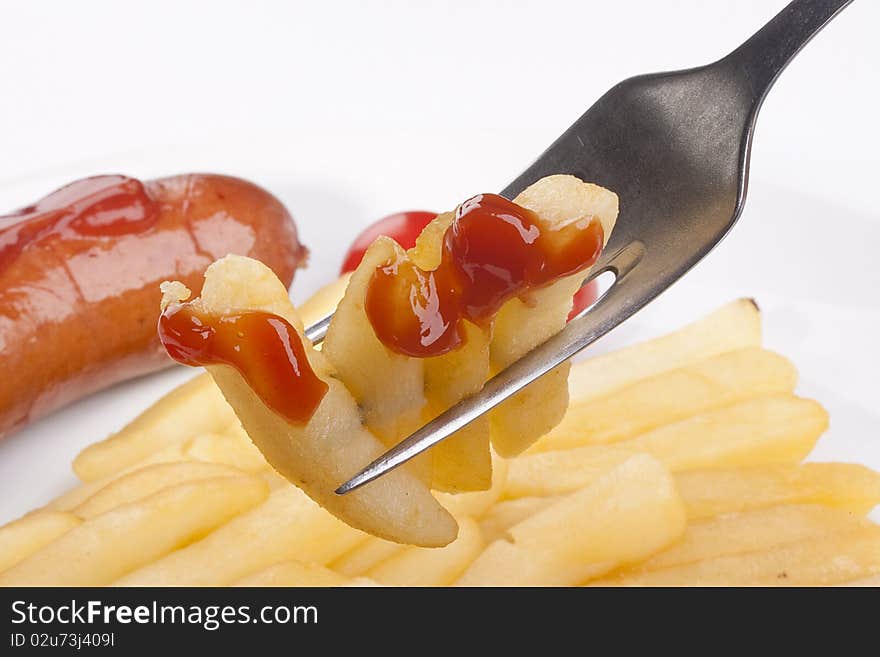 Fried potato on a fork, in a plate tomatoes and sausage.