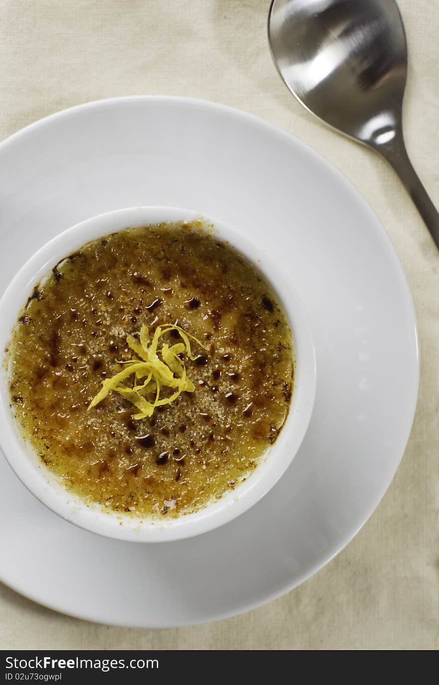 Creme brulee desert on white plate with a spoon. French culture cuisine. Creme brulee desert on white plate with a spoon. French culture cuisine.