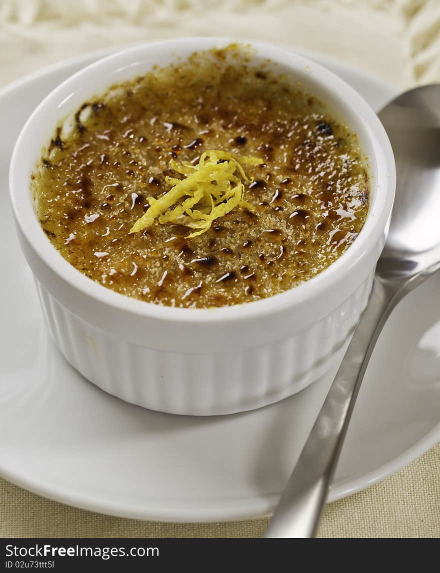 Creme brulee desert on white plate with a spoon. French culture cuisine. Creme brulee desert on white plate with a spoon. French culture cuisine.