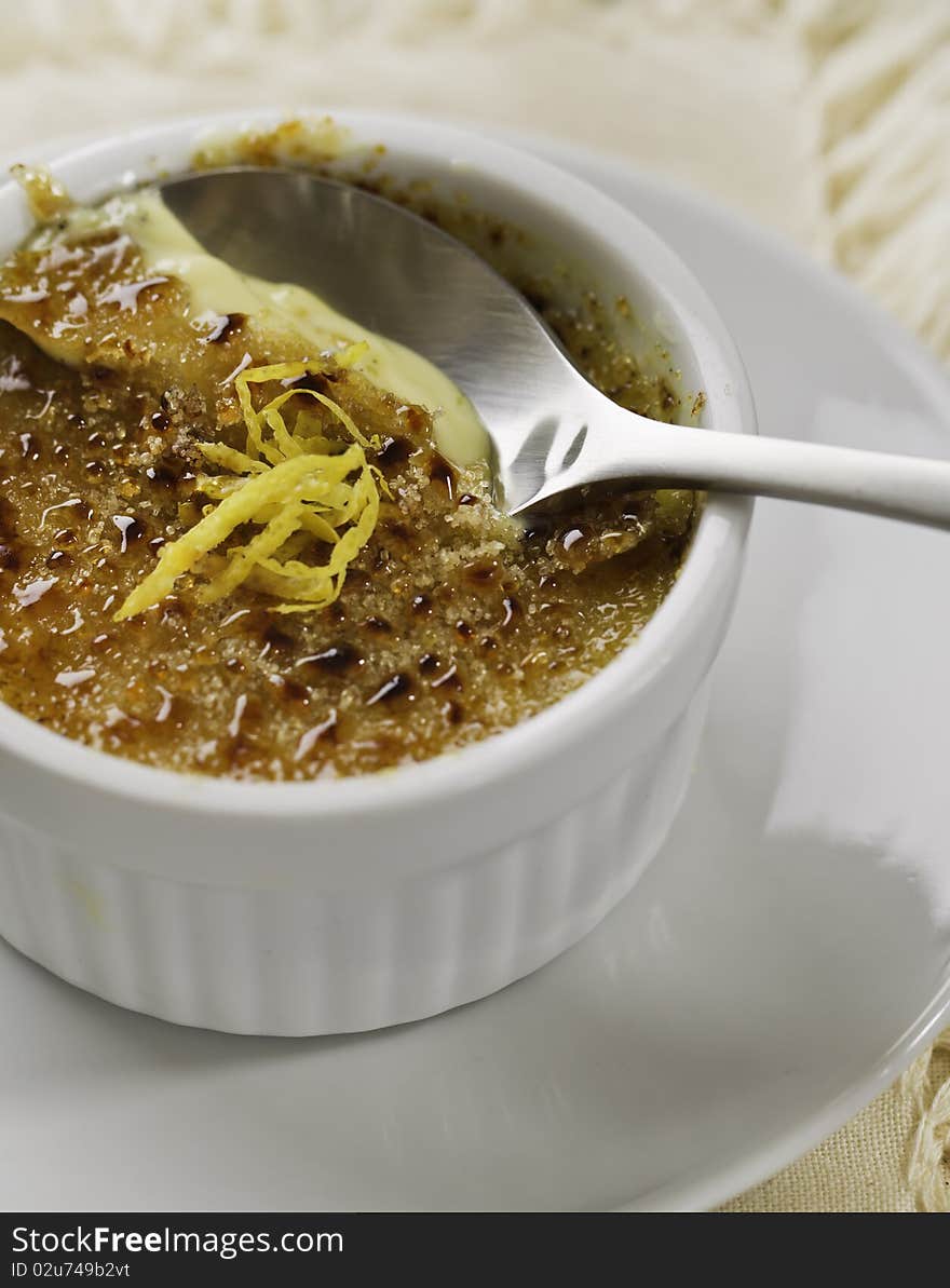 Creme brulee desert on white plate with a spoon. French culture cuisine.