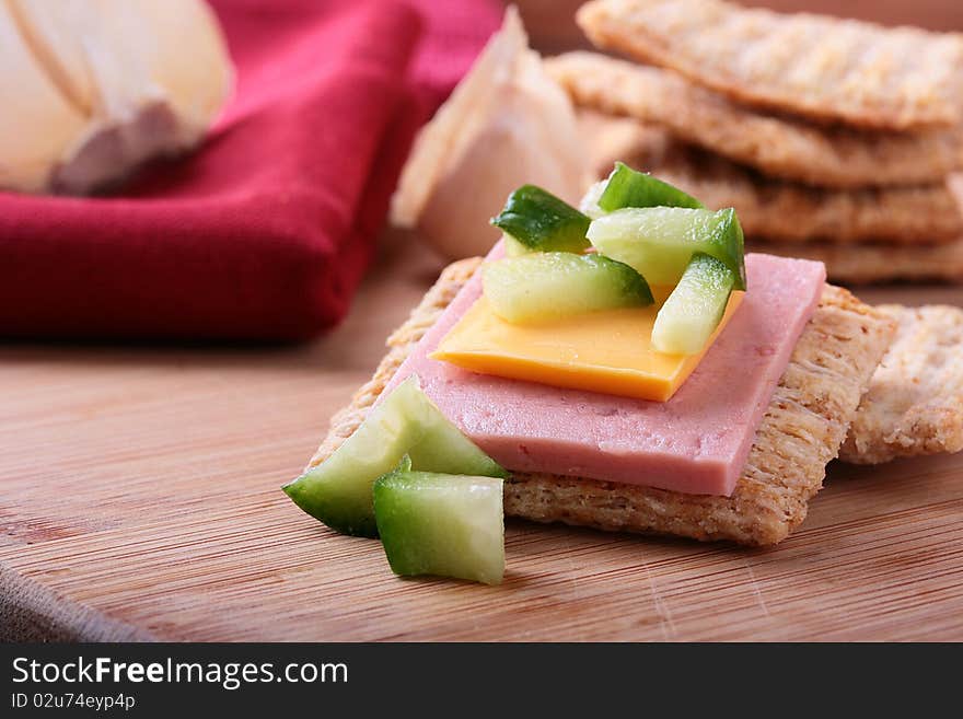 Wheat crackers on a kitchen board with cheese and cucumber. Wheat crackers on a kitchen board with cheese and cucumber.