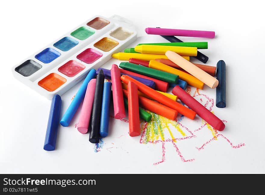 Watercolours and heap of colourfull crayons on white background