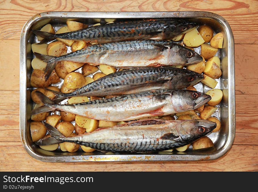 Uncooked fish with potatoes in pan ready to be roast