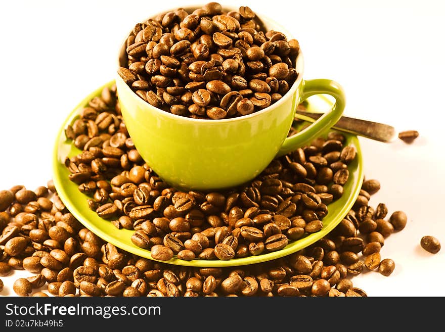 Green cup of coffee with brown beans on white ground