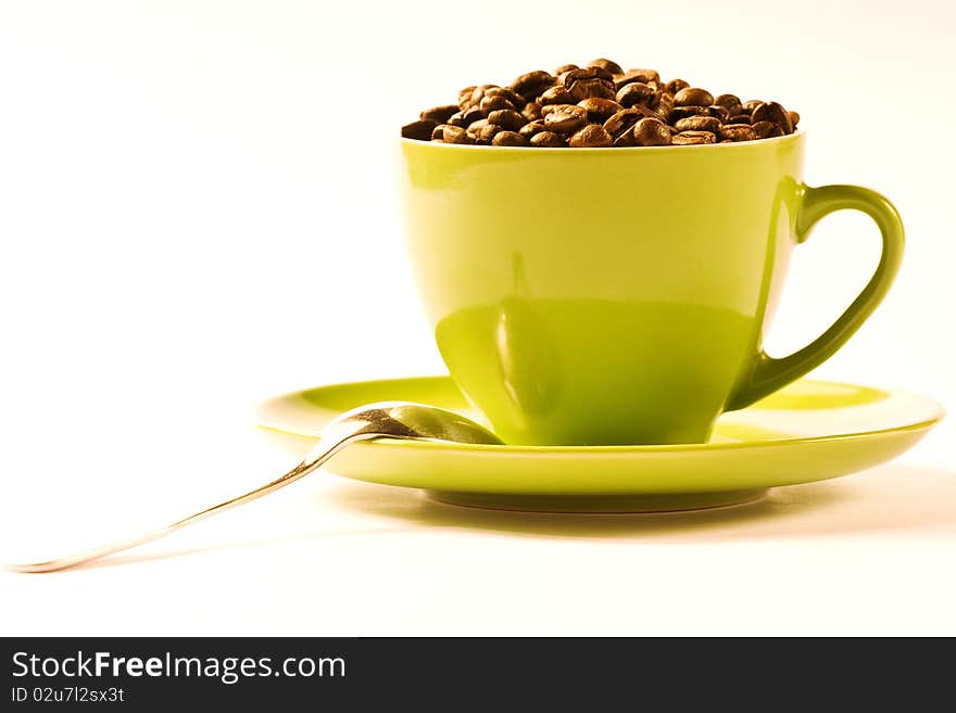 Green cup of coffee with brown beans on white ground