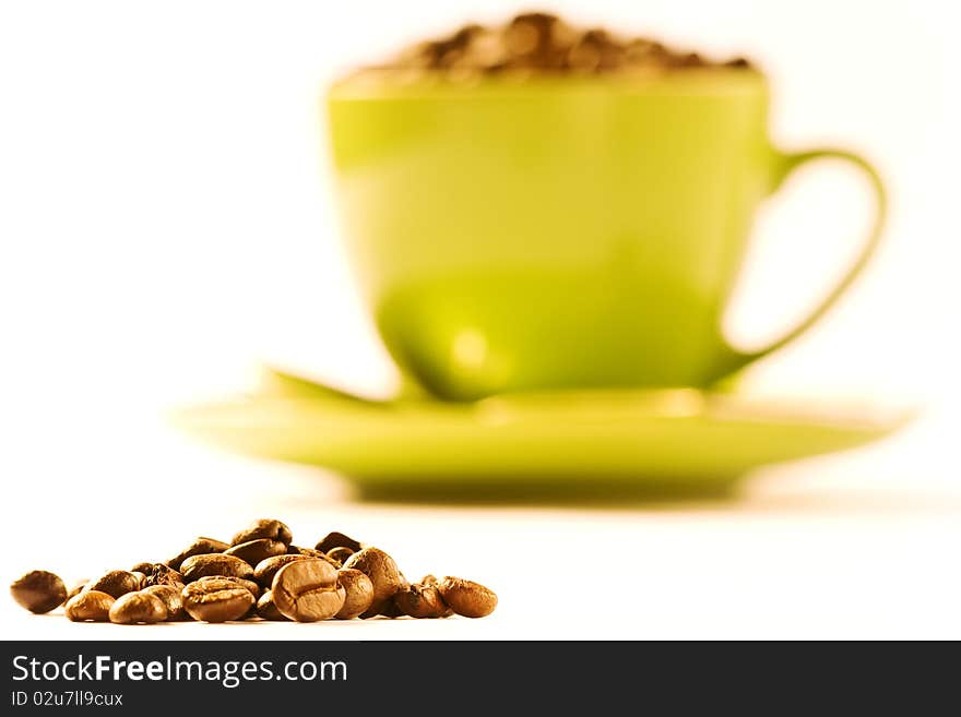 Green cup of coffee with much brown beans