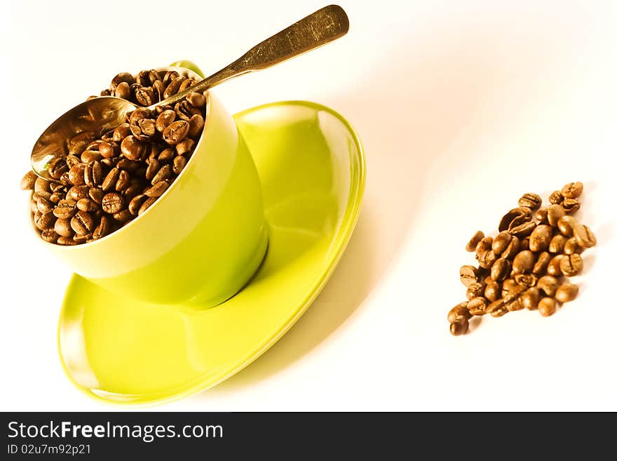 Green cup of coffee with brown beans on white ground