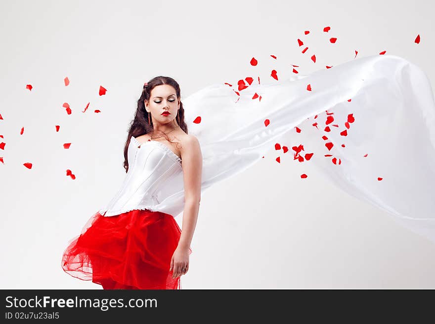 Young beautiful woman with petals of roses, on a white background