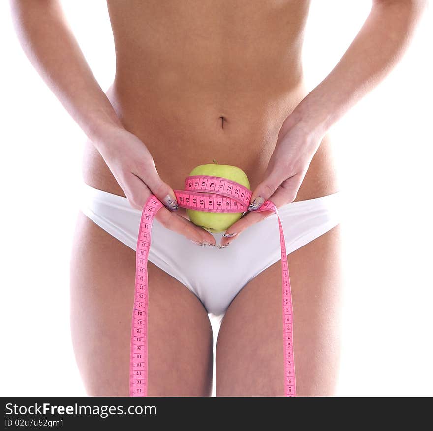 A young woman is measuring a green apple